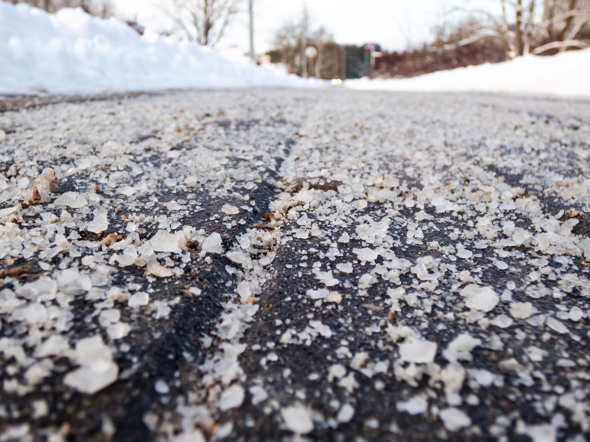 Macro shot of salt grains on icy sidewalk surface in the winter